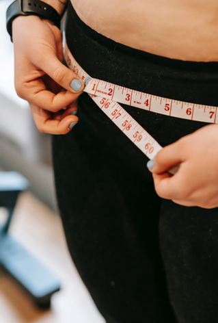 person measuring their waist